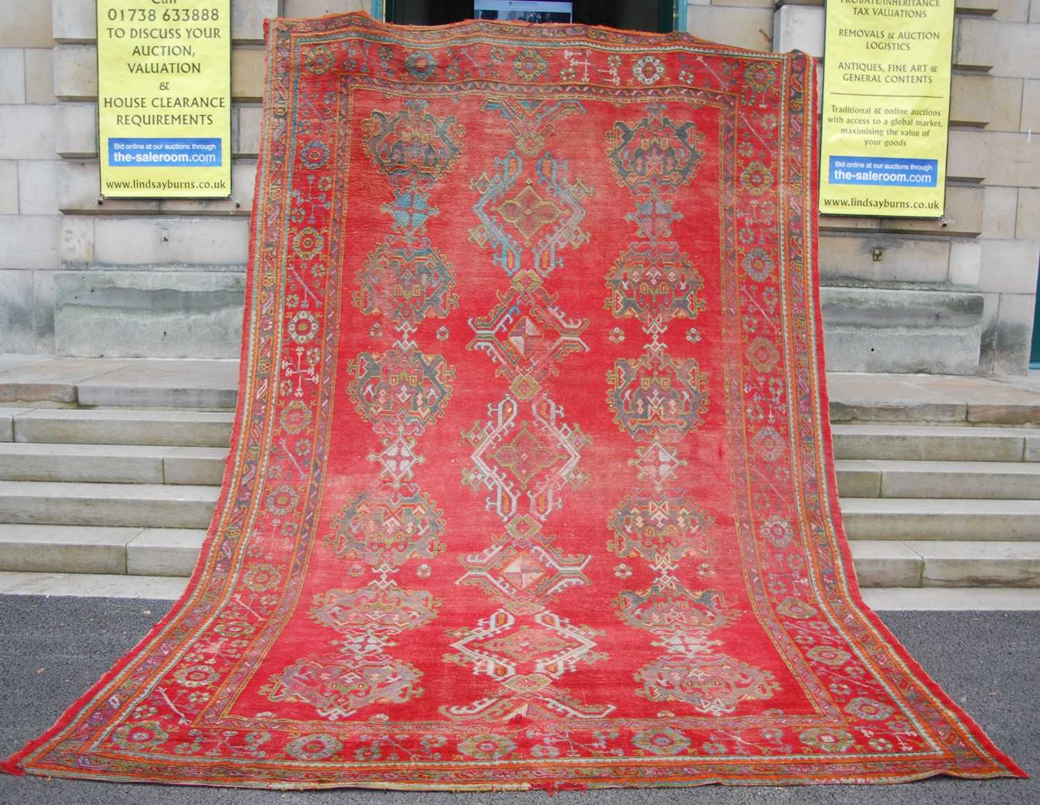 A late 19th century red ground Ushak carpet, the rectangular field decorated with three rows of