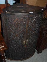 A Jacobean style carved oak hanging corner cupboard.