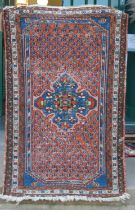 A Persian mat, early 20th century, the madder ground centred with a blue floral medallion surrounded