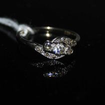 A white metal and diamond set three stone ring with diamond line shoulders, stamped 'PLAT', ring
