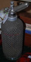 A vintage Seltzer soda syphon with wire mesh overlay.