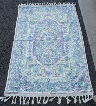 A white ground tasseled rug with repeating borders of stylised flowers in shades of purple and