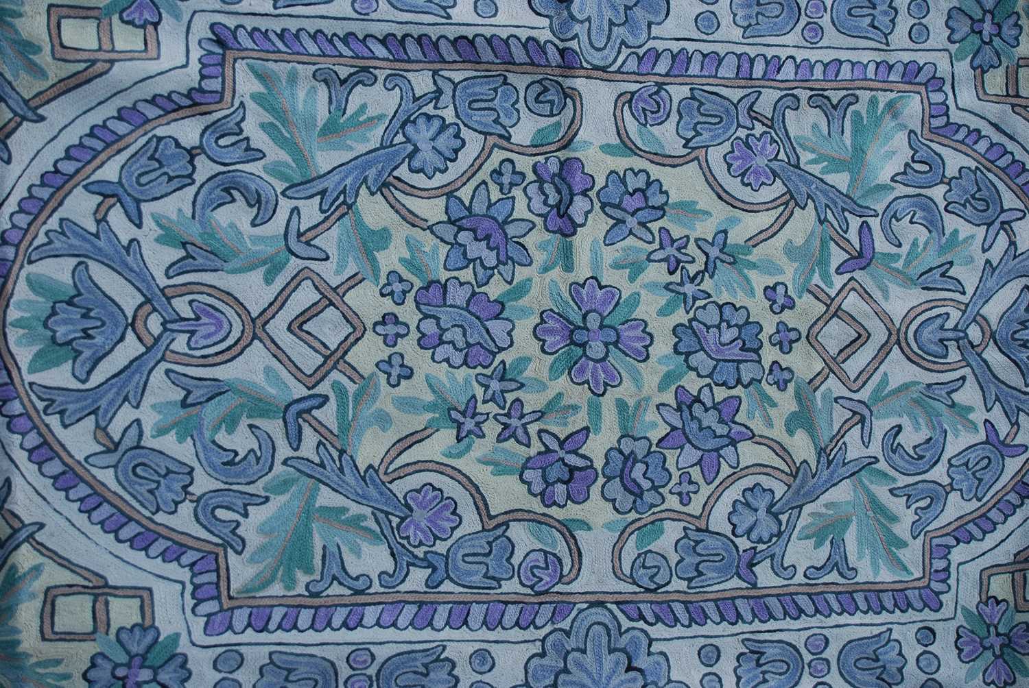 A white ground tasseled rug with repeating borders of stylised flowers in shades of purple and - Image 3 of 4