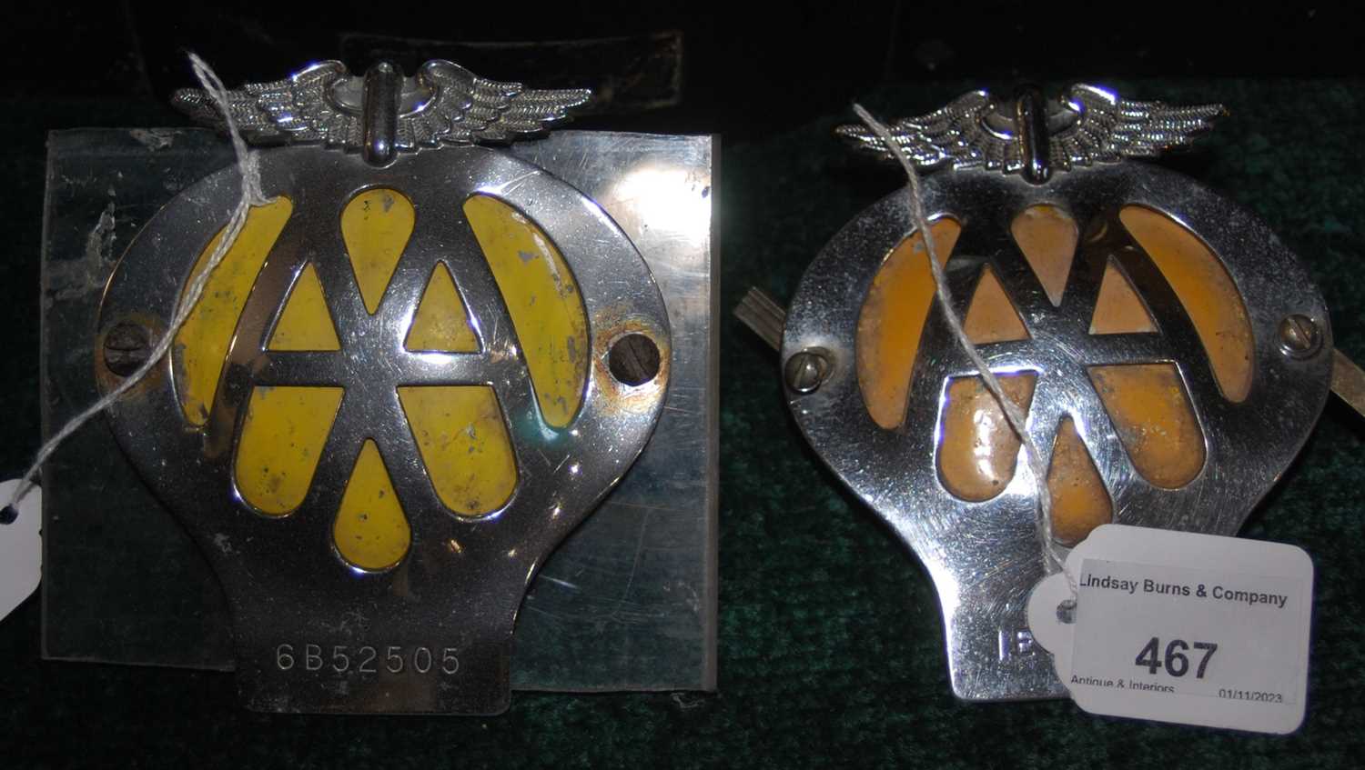 Two AA car badges numbers 6B52505, and 1E84264.