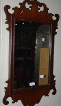 A mahogany fret cut rectangular wall mirror together with another dark wood oval wall mirror.