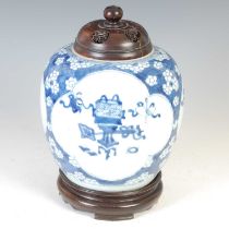 A Chinese porcelain blue and white jar and wooden cover and stand, Qing Dynasty, decorated with