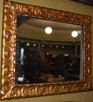 A gilt framed rectangular wall mirror with foliate detail, 55cm x 65cm.