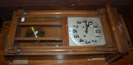 An oak framed wall clock with Arabic numeral dial and twin train movement.