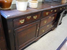 A George III oak dresser base, the rectangular top with moulded edge above a central bank of three