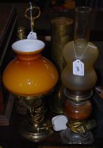 A brass oil lamp converted to electricity with orange glass shade with white inner, together with