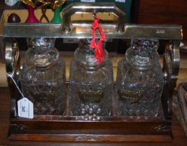 An oak and EP mounted whisky tantalus with three cut glass decanters and stoppers, each with a
