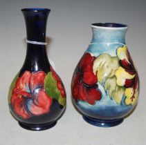 Two Moorcroft pottery vases comprising a dark blue ground bottle vase decorated with hibiscus,