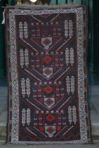 A Persian rug, early 20th century, the rectangular earth coloured field decorated with four stylised