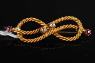 A late 19th / early 20th century yellow metal rope lovers knot brooch, set with rubies and diamonds,