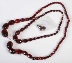 Two vintage red amber type bead necklaces of faceted form, together with a pair of earrings.