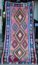 A Kilim type long rug, 20th century, the abrashed pink rectangular field centred with three multi-