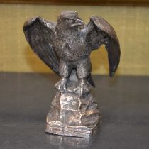 A white metal model of an eagle, modelled standing on a rocky outcrop with wings outstretched, 10.