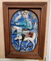 A 19th century Persian pottery plaque, worked in shallow relief with a fawkner on horseback,