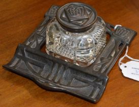 A Glasgow style cast iron desk stand, set with a moulded glass inkwell with detachable cover, with