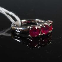 A white metal and composite ruby glass three stone ring, set with three round faceted composite