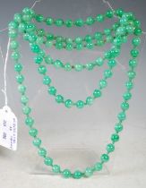 A long green jade bead necklace, together with a pair of matching earrings.