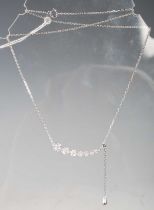 A white metal and diamond set adjustable necklace, set with a graduated row of seven stylised