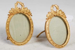 A pair of early 20th century gilt metal oval strut-back photograph frames with laurel wreath