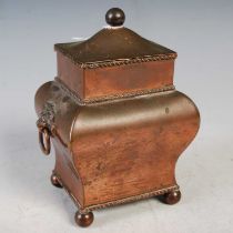 A Regency style copper tea caddy with hinged cover, lion mask terminals and four bun feet, enclosing