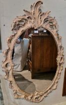 A composite Rococo style oval wall mirror with pierced foliate and scroll detail, overall 112cm x