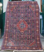 A Persian rug, early 20th century, the rectangular blue ground centred with a madder coloured