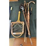 Collection of walking sticks together with a tennis racket and shooting stick