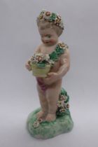 A porcelain figure of a putto on flower encrusted base