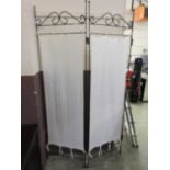 A metalwork three fold screen with white fabric panels
