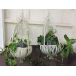 A pair of white metal painted hanging planters with plants