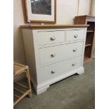 A modern oak topped cream base chest of two short over two long drawers