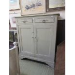 A grey painted cabinet having two drawers above two cupboard doors