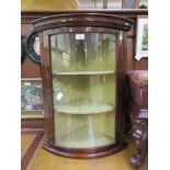 An Empire style mahogany bow front wall hanging corner cupboard with glazed door