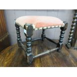 An early 20th century oak framed stool with pink fabric seat