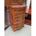 A reproduction yew veneered serpentine chest of three drawers