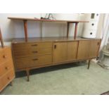 A mid-20th century teak veneered sideboard by Nathan with three drawers alongside two sliding