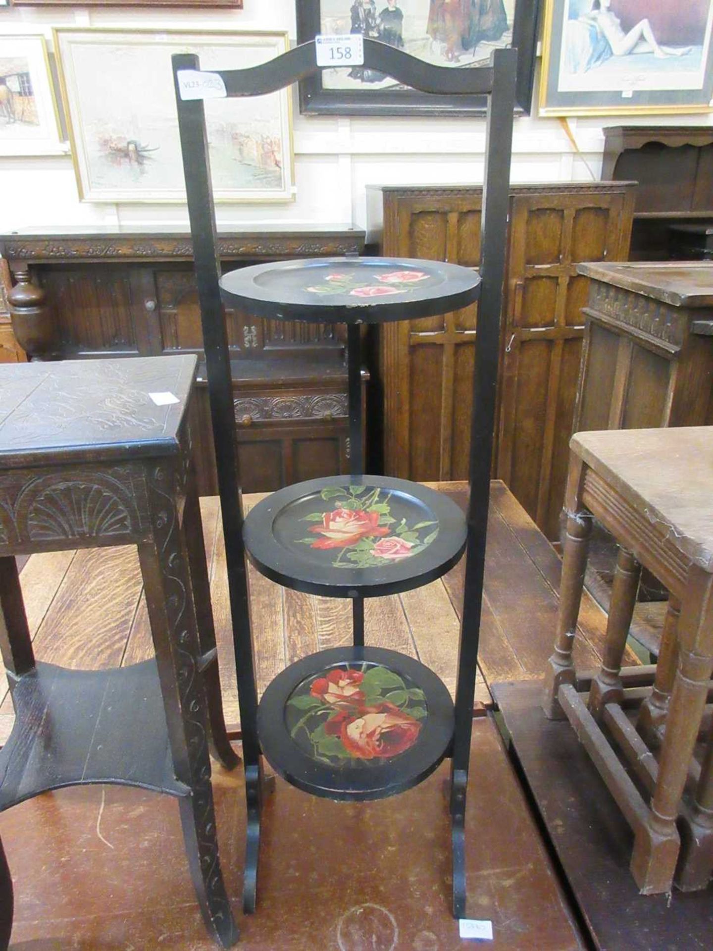 A black painted three tier cake stand with floral painted design