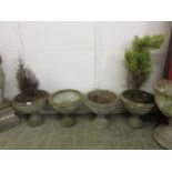 A set of four matching composite stone garden urns, two with plants