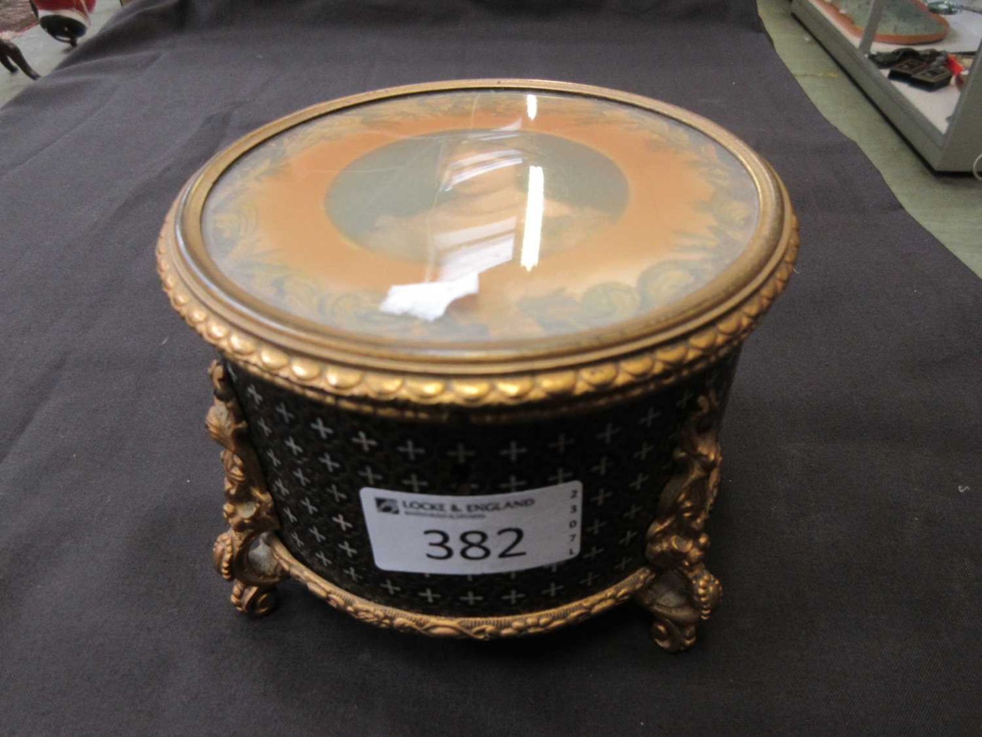 A black and gilt trinket box with glazed print of young girl to lid