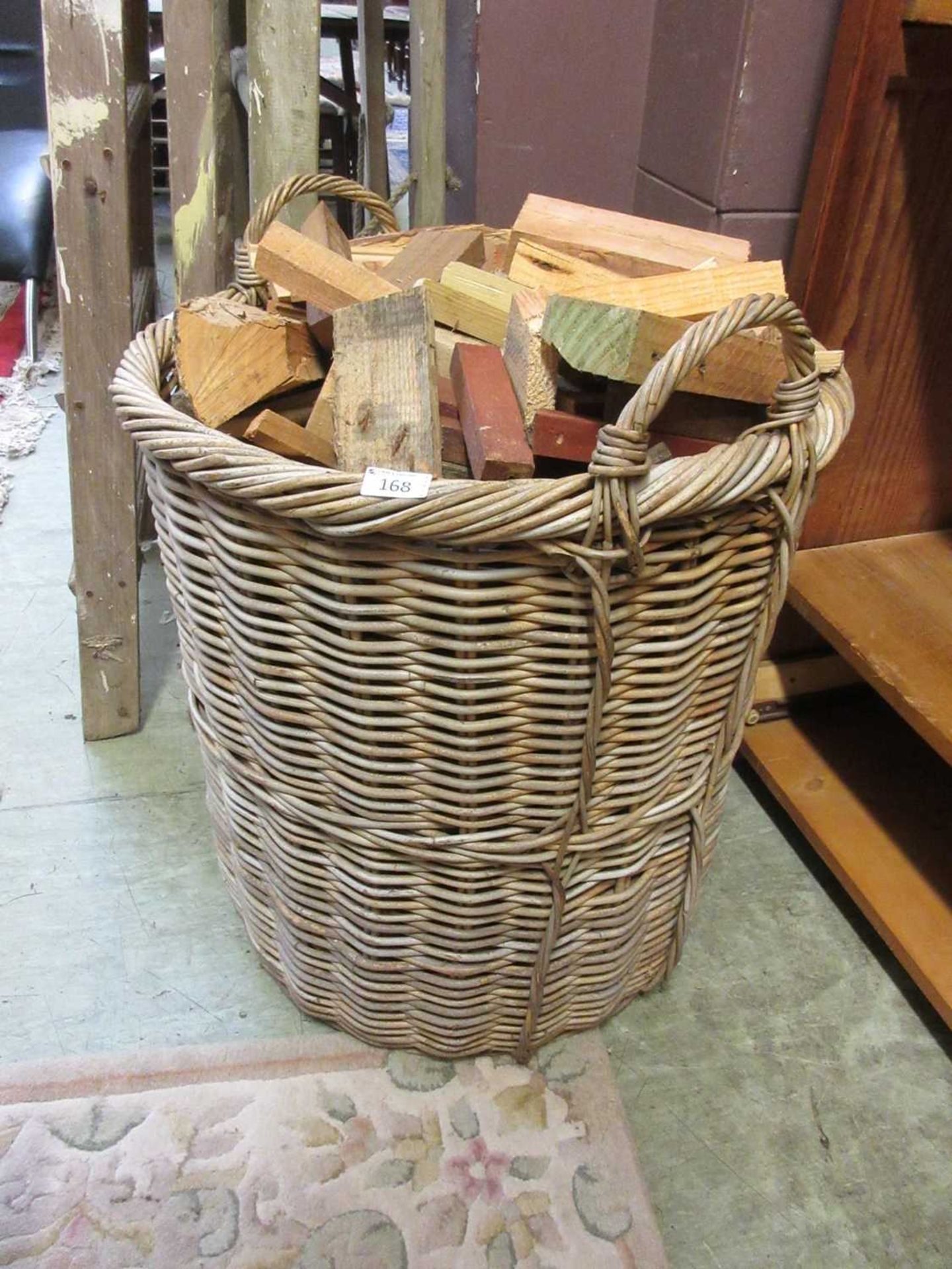 A large wicker log bin containing logs