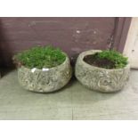 A pair of composite garden pots with floral design bodies