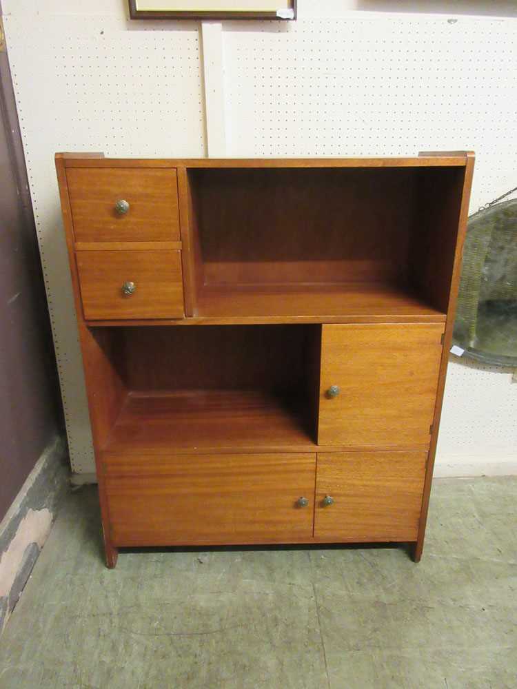 A mid-20th century teak storage unit with drawers, shelves, and cupboard doors