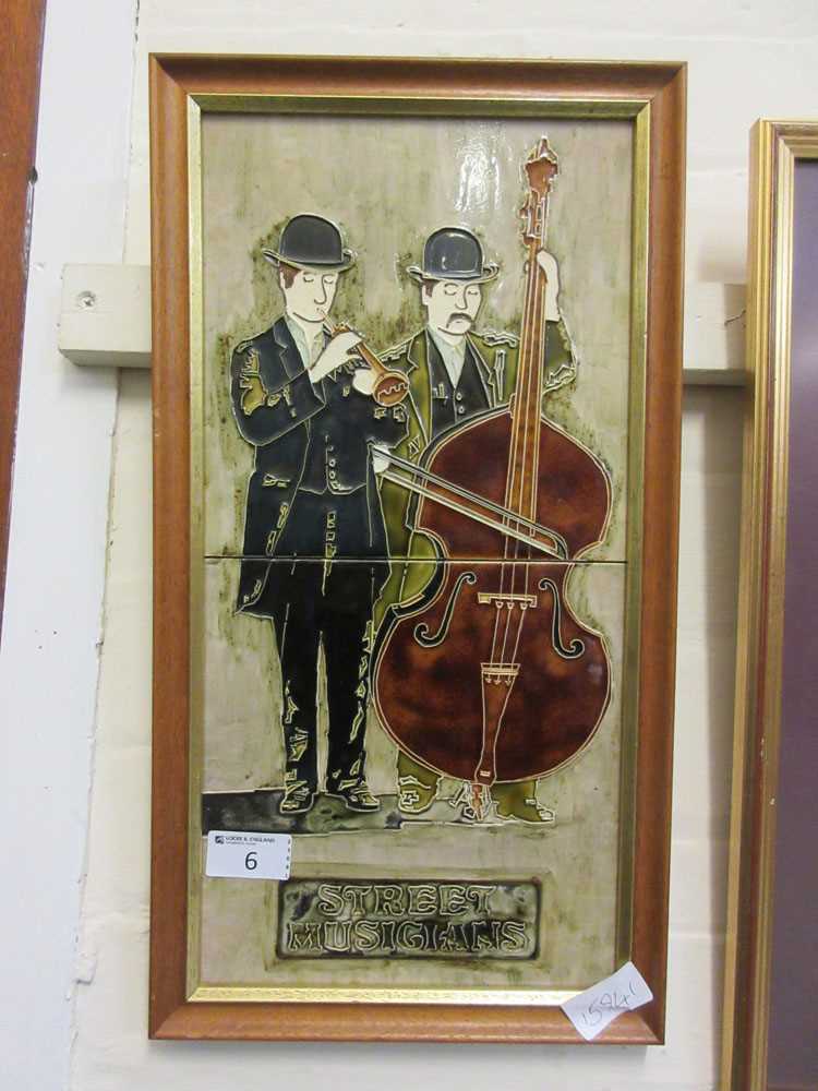 A framed ceramic tile of street musicians