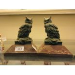 A pair of metalwork owls on marble plinths