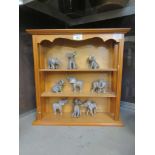 A pine shelf unit containing nine moulded miniature elephants