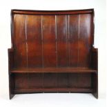 An 18th century oak settle, the bowed boarded back with wing arms and single plank seat, h. 149